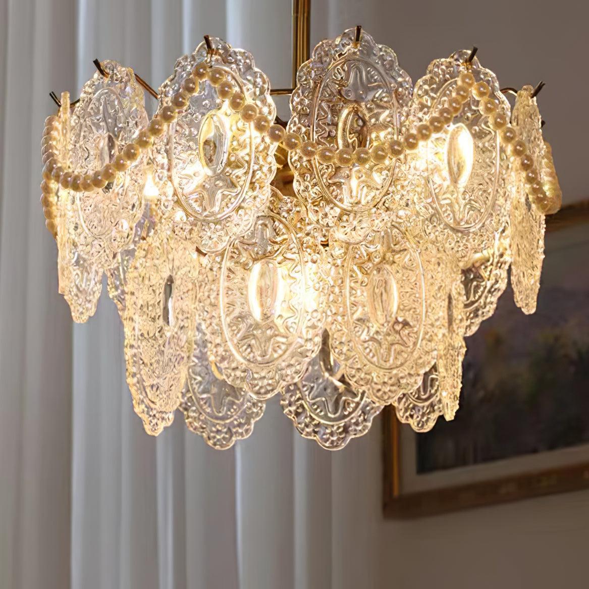 Close view of the embossed glass panels and swags of pearl beads on this lit Clérachic chandelier, with curtains behind.