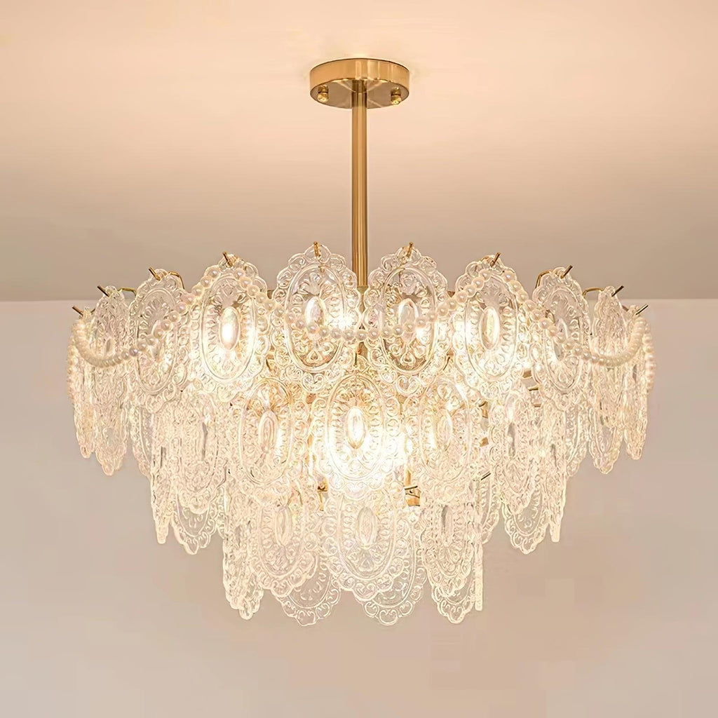 Looking up at a lit Clérachic chandelier with layered glass panels and pearl strands, against a pale ceiling.