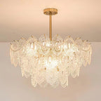 Looking up at a lit Clérachic chandelier with layered glass panels and pearl strands, against a pale ceiling.