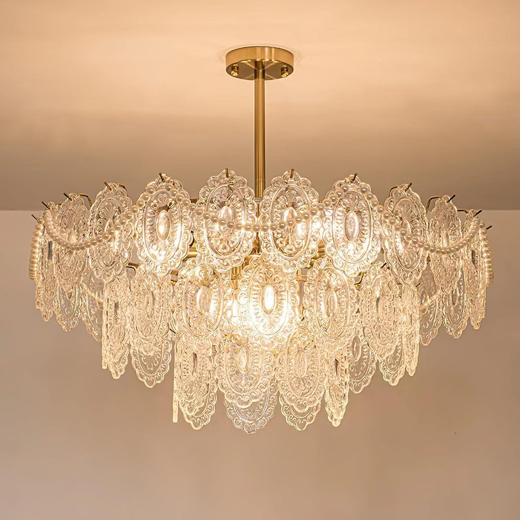 Lit Clérachic chandelier with layered patterned glass and pearl strands, hanging from a gold rod under a peach ceiling.