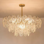 Lit Clérachic chandelier with layered patterned glass and pearl strands, hanging from a gold rod under a peach ceiling.