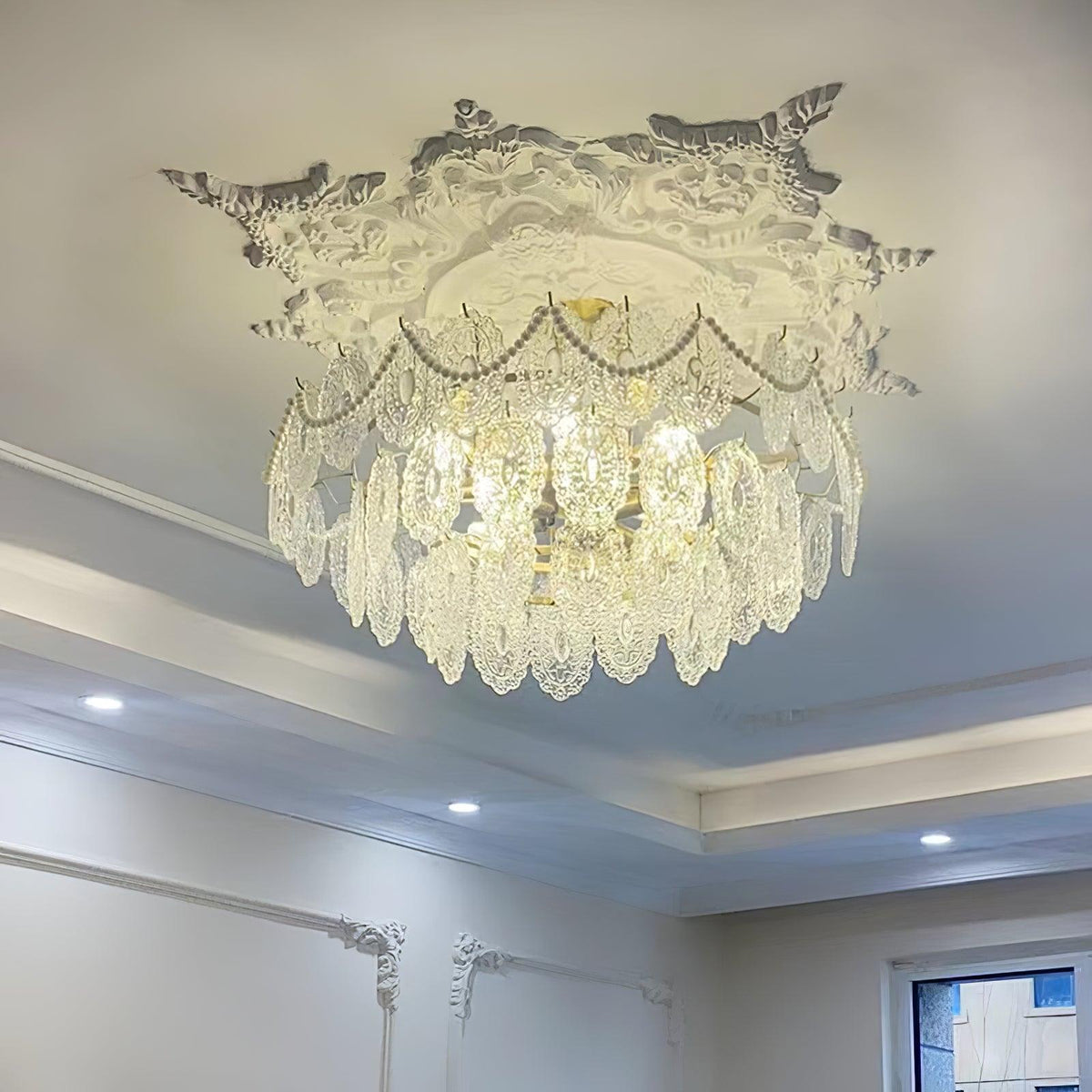 Clérachic chandelier fitted against a decorative plaster ceiling rose, with pearl strands and spotlights in the ceiling.