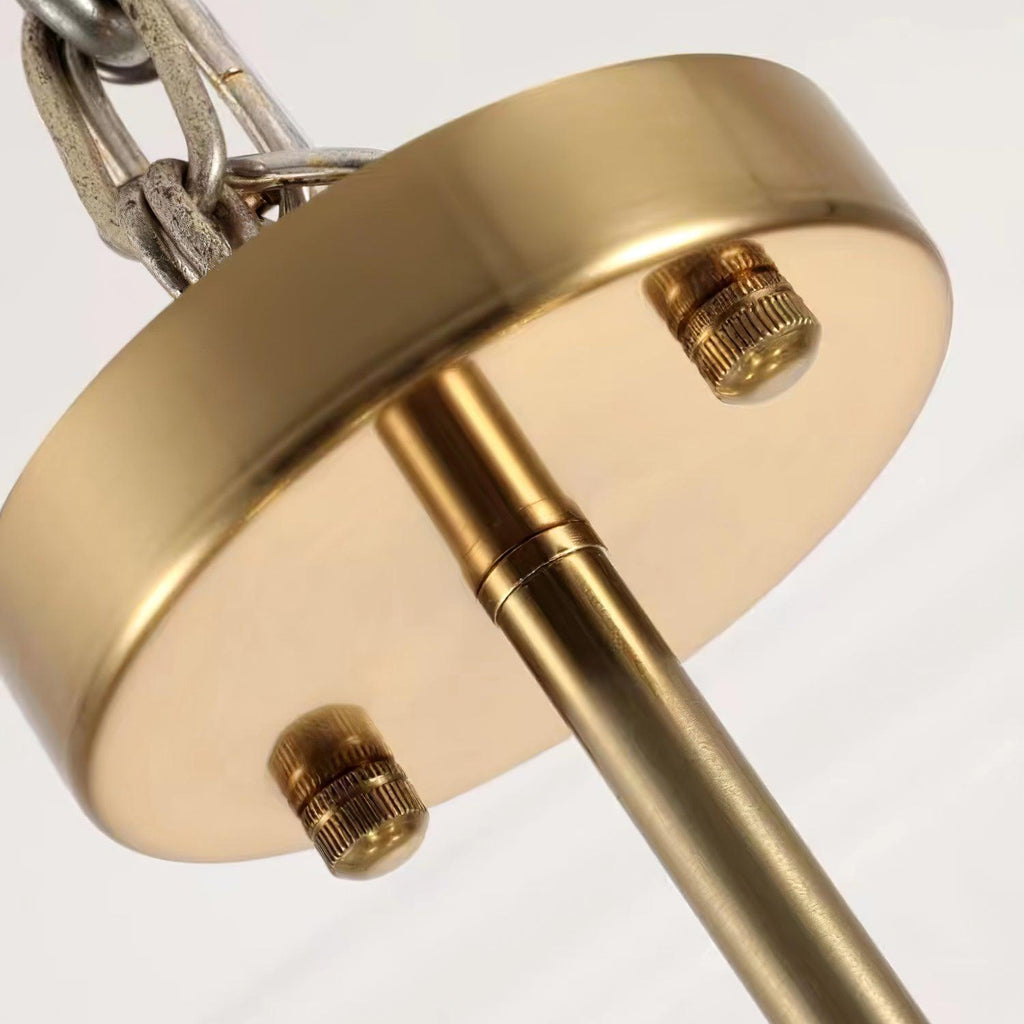 Close view of the round brushed-gold ceiling plate on this Clérachic chandelier, with two knurled screws and a chain.