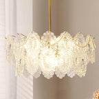 Close view of a Clérachic chandelier hung before a pale wall, with embossed glass leaves and pearl beads lit within.