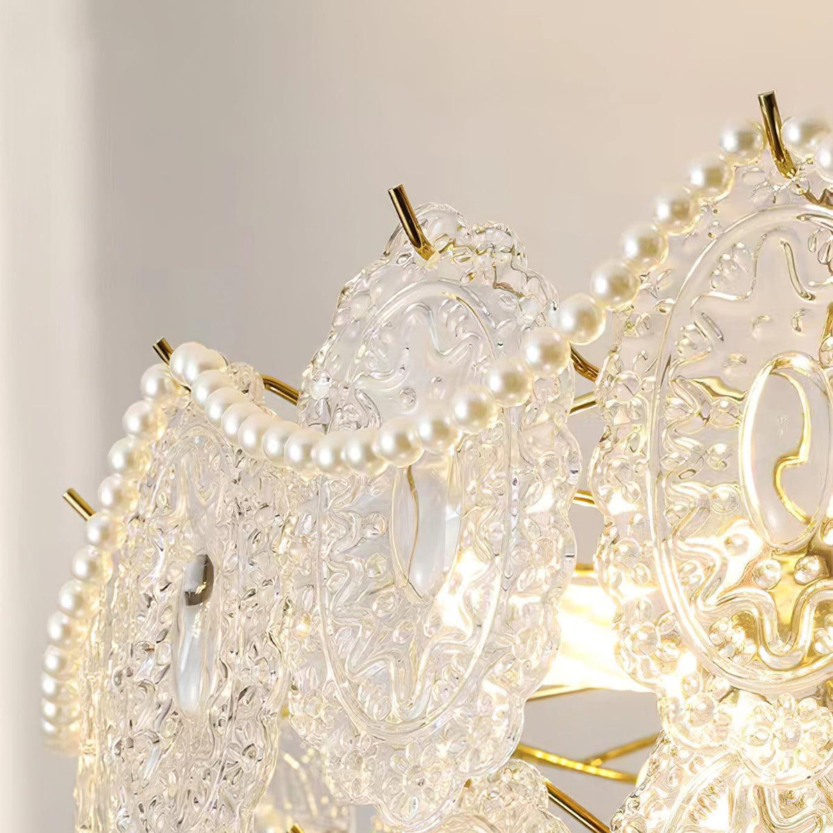 Close-up of one embossed glass panel and a strand of pearl beads on this Clérachic chandelier, with a gold prong.