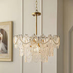Clérachic chandelier on a gold rod and chain, with pearl swags, in front of a panelled wall and a framed painting.
