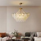 This Clérachic pendant light hangs above a living room with cream and green sofas, a throw blanket and a round dark-topped coffee table.