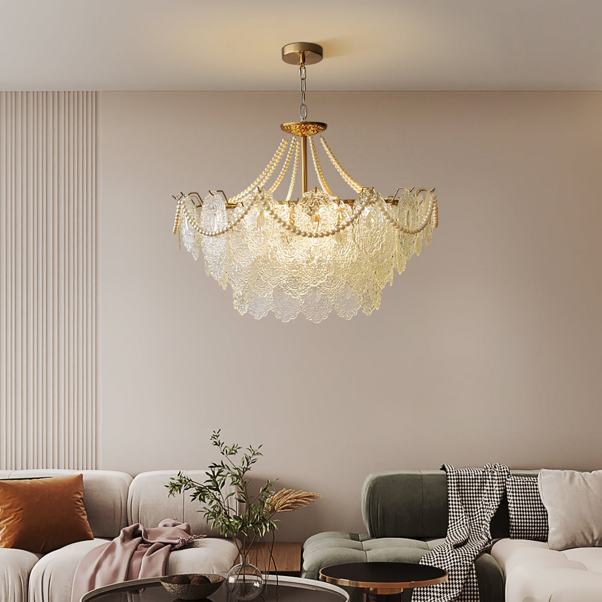 This Clérachic pendant light hangs above a living room with cream and green sofas, a throw blanket and a round dark-topped coffee table.