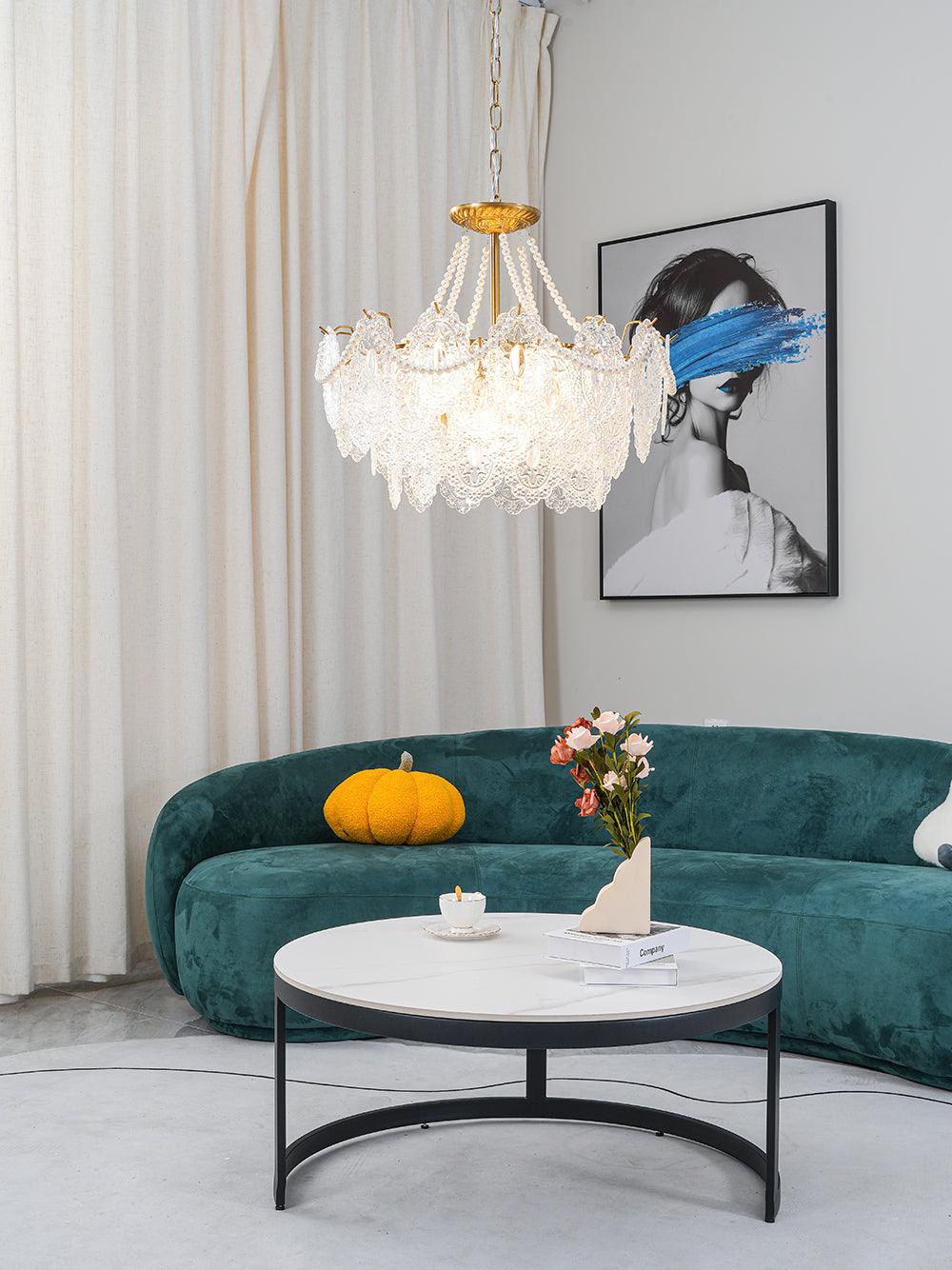 Clérachic glass and pearl pendant hanging between sheer curtains and a framed portrait, above a green sofa and a white round table.