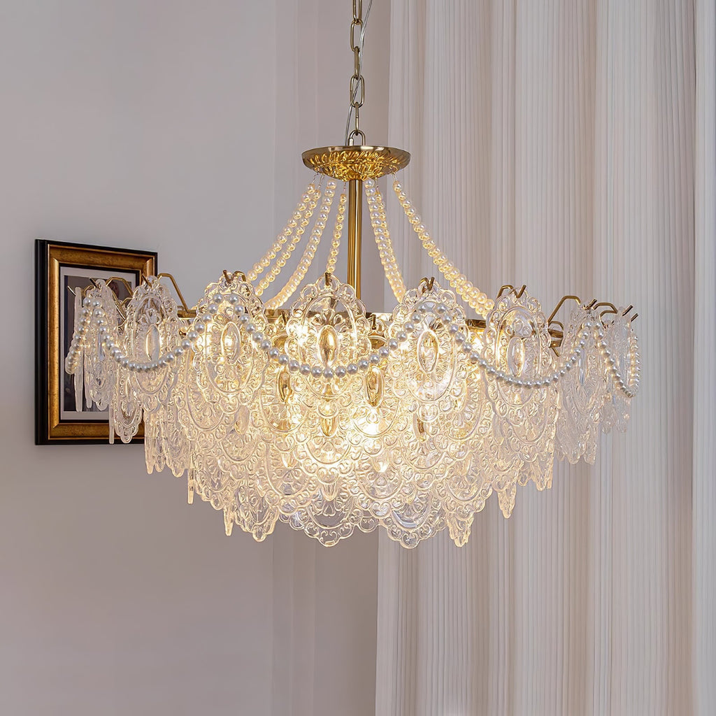 Wide Clérachic pendant light lit beside a gilt-framed portrait, with pearl swags draped over clear glass panels and a gold central stem.