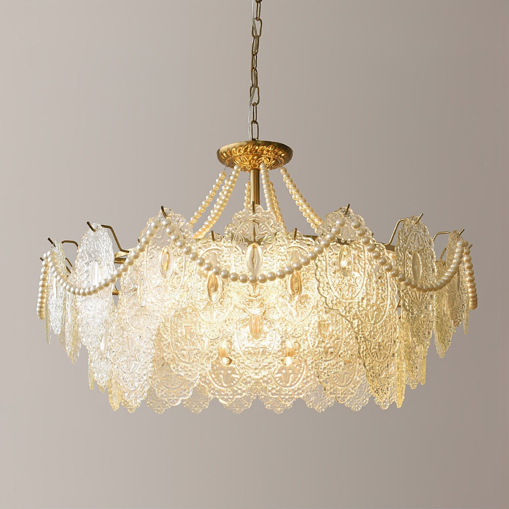 Straight-on view of the lit Clérachic pendant, with its tiers of embossed clear glass and loops of pearl strands on a plain wall.