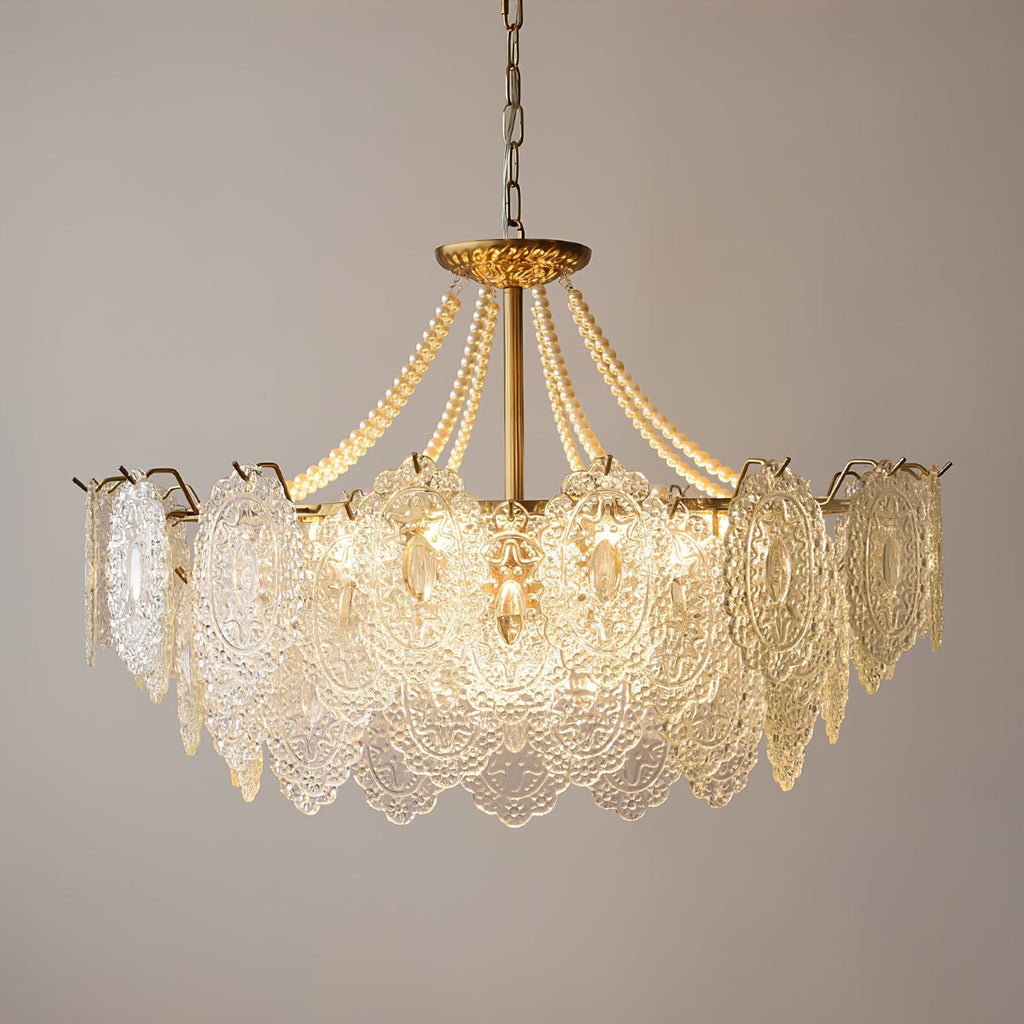 Clérachic pendant with a gold stem and pearl strands, lit from within and photographed against a soft taupe wall.