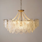 Clérachic pendant with a gold stem and pearl strands, lit from within and photographed against a soft taupe wall.