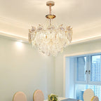 Lit Clérachic pendant in a dining room with white cornice lighting, pale green walls, a window and white chairs at the table below.