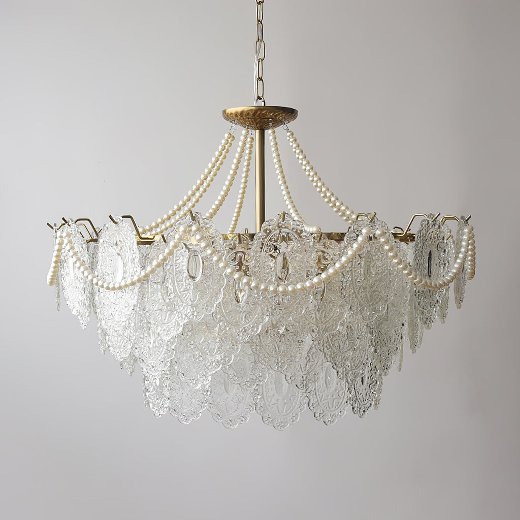 A Clérachic pendant seen with its lights off, with clear embossed glass panels, pearl swags and a gold canopy on a pale grey wall.