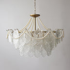 A Clérachic pendant seen with its lights off, with clear embossed glass panels, pearl swags and a gold canopy on a pale grey wall.
