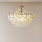 Smaller-looking Clérachic pendant with a rounded skirt of embossed glass and pearl swags, lit against a plain warm-grey wall.