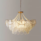Clérachic pendant with a compact skirt of embossed glass petals, pearl strands and gold wire tips, lit against a grey wall.