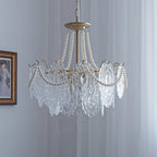 The Clérachic pendant with its lights off, showing clear embossed glass petals and pearl strands against a pale curtain and a framed portrait.
