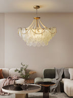 Seen from a distance, the Clérachic pendant hangs in a living room with a cream curved sofa, a green sofa and two round tables.