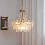 A Clérachic pendant lit beside a gilt-framed portrait, with a bright bulb glowing through its embossed glass and pearl swags.