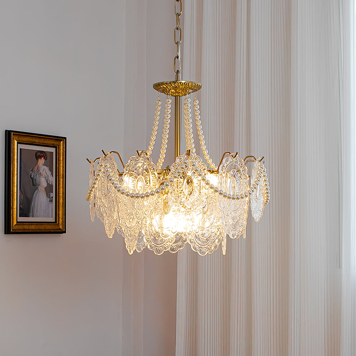 A Clérachic pendant lit beside a gilt-framed portrait, with a bright bulb glowing through its embossed glass and pearl swags.