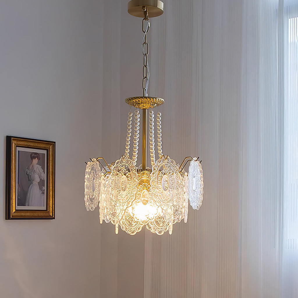 Clérachic pendant with a shorter, straighter glass skirt and pearl strands, lit beside a gilt-framed portrait and a sheer curtain.
