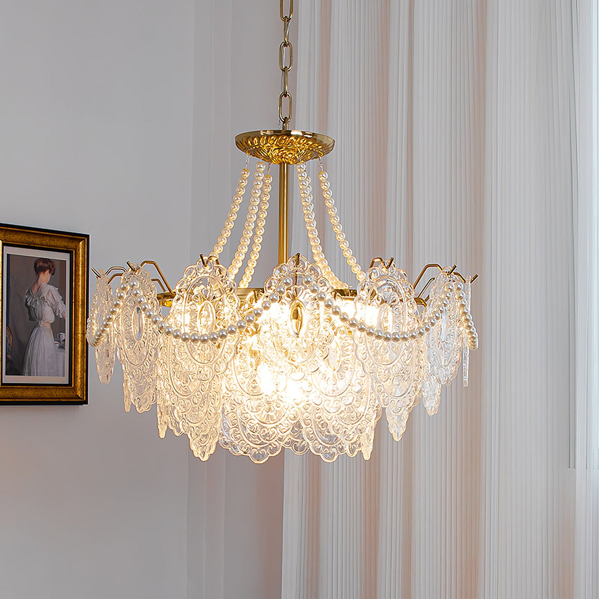 Clérachic pendant with a gold ceiling plate and pearl strands, lit at an angle beside a gilt-framed portrait and a pleated curtain.