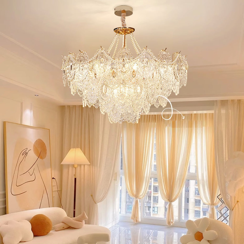 A Clérachic pendant light glowing above a warm cream living room with gathered curtains, a floor lamp and a framed line drawing.