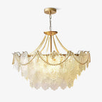 This Clérachic pendant with embossed glass panels, pearl swags and a gold canopy on a chain, lit and shown on a plain light backdrop.