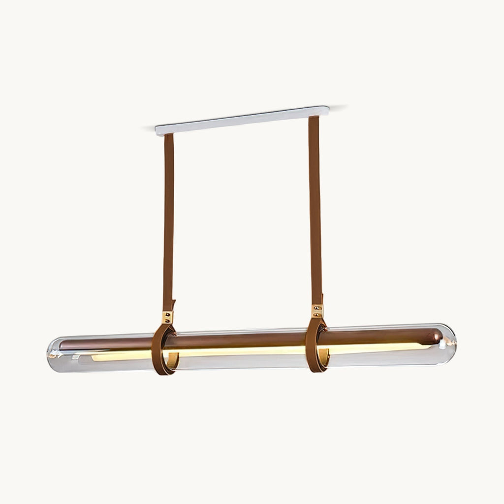 This Clérachic linear pendant on a plain white backdrop, with a long glass tube held by two brown leather straps from a white ceiling plate.