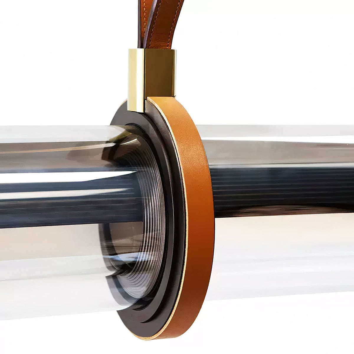 Close view of a brown leather loop and brass collar gripping the clear glass tube of this Clérachic pendant.