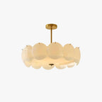 Round pendant of overlapping white glass discs on a brass stem and canopy, lit warm, on a plain white backdrop, from Clérachic.