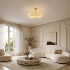 Clérachic glass-disc pendant hanging in a panelled living room with a curved cream sofa and a marble-topped coffee table.