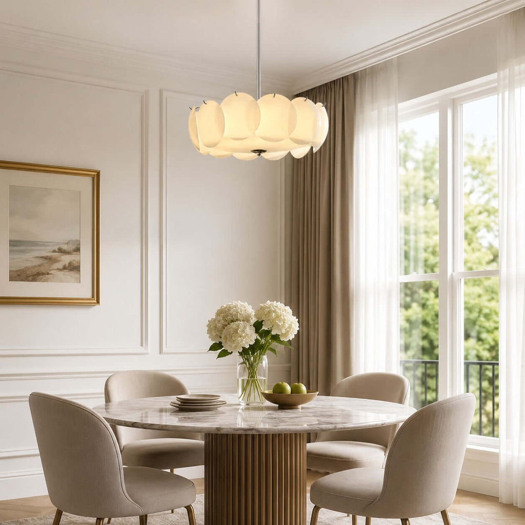 Clérachic pendant on a long thin chrome rod over a round dining table, with tall windows and a framed seascape beside it.