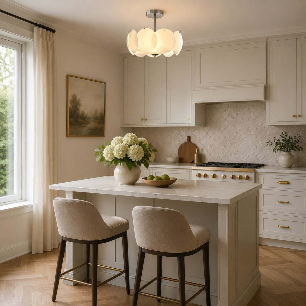 Chrome Clérachic pendant of white glass petals above a kitchen island with two cream stools and a marble worktop.