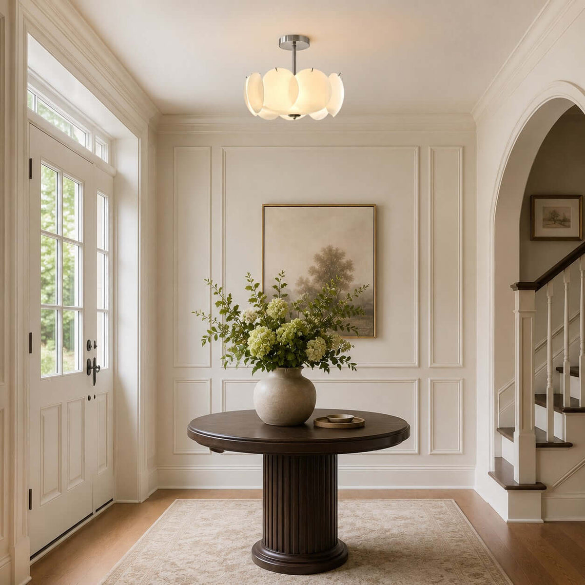 Small Clérachic pendant glowing in an entrance hall with an arched doorway, a round dark wood table and a vase of greenery.