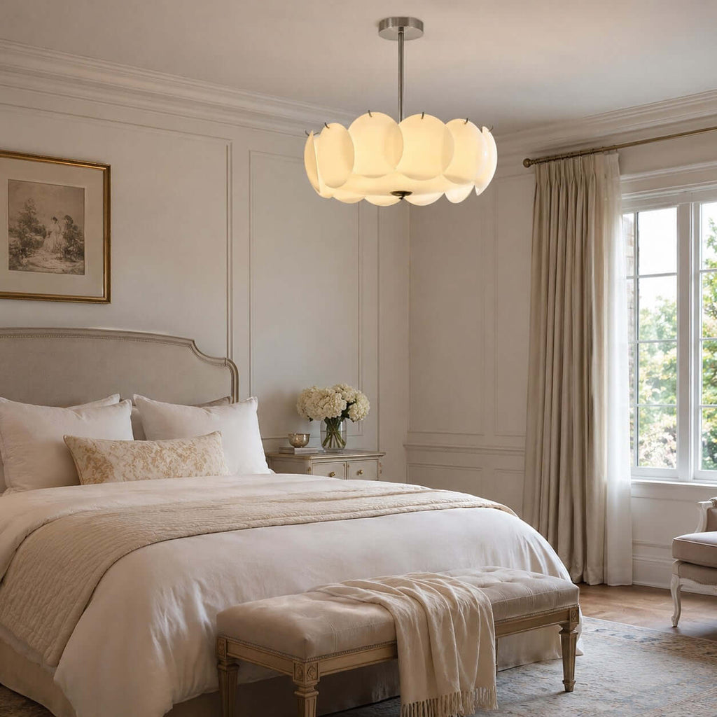 Clérachic glass-disc pendant in a bedroom with an upholstered headboard, a cream bench and linen curtains by the window.