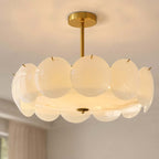 Close view of the overlapping white glass discs and brass canopy on this Clérachic pendant, lit warm from within.