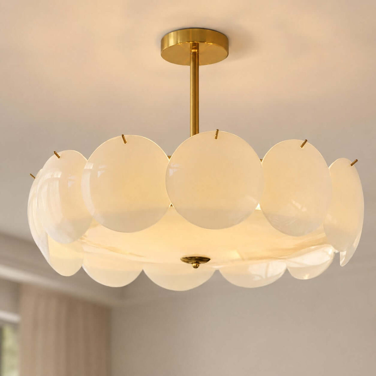 Close view of the overlapping white glass discs and brass canopy on this Clérachic pendant, lit warm from within.