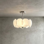 Smaller chrome Clérachic pendant with overlapping glass discs, glowing against a textured grey plaster wall.