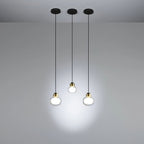 Three Clérachic glass pendants hang at different heights from black ceiling canopies, lighting a plain grey wall.