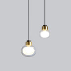 Two Clérachic glass pendants with gold collars hang at different heights, the larger size lower, against a light grey backdrop.