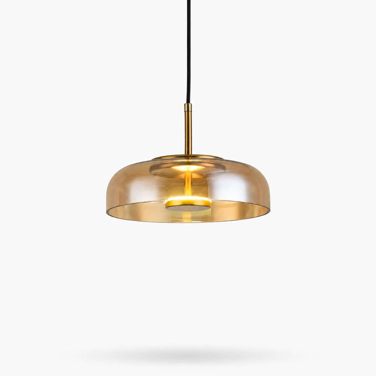 Amber glass Clérachic pendant light on a white backdrop, a wide shallow dome with a brass stem and a lit LED disc inside.