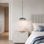 Smoke grey glass Clérachic pendant light hanging over a marble bedside table, with a ribbed headboard and blue bedding beside it.