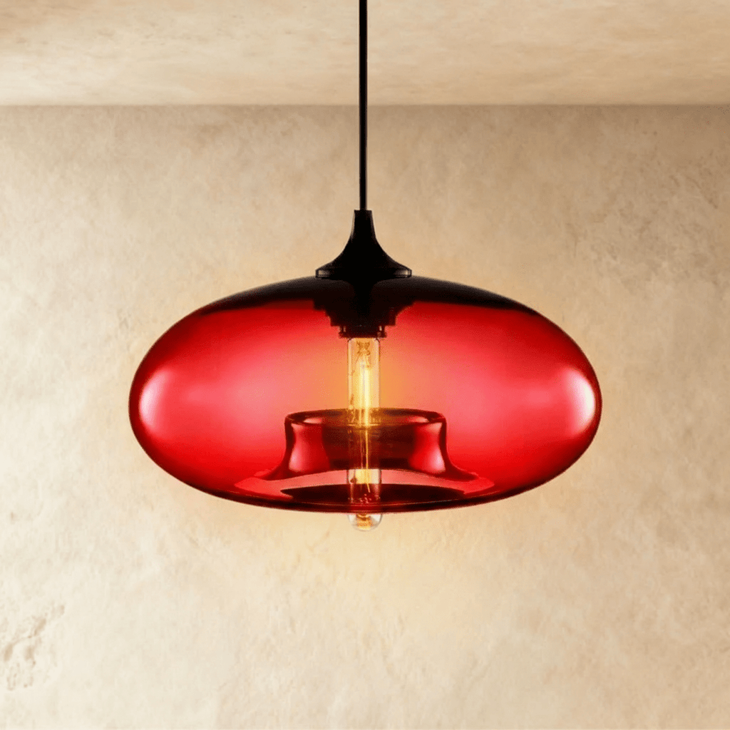 Clérachic pendant light with a glowing red blown-glass oval shade, black cap and cord, and a warm tube bulb inside.