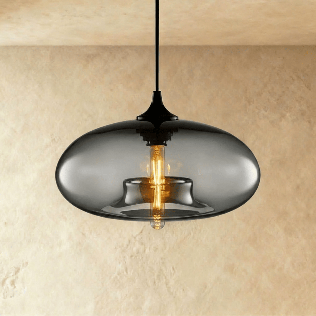 Clérachic pendant light with a smoked-grey oval glass shade lit by an amber tube bulb, black cord and cap above.