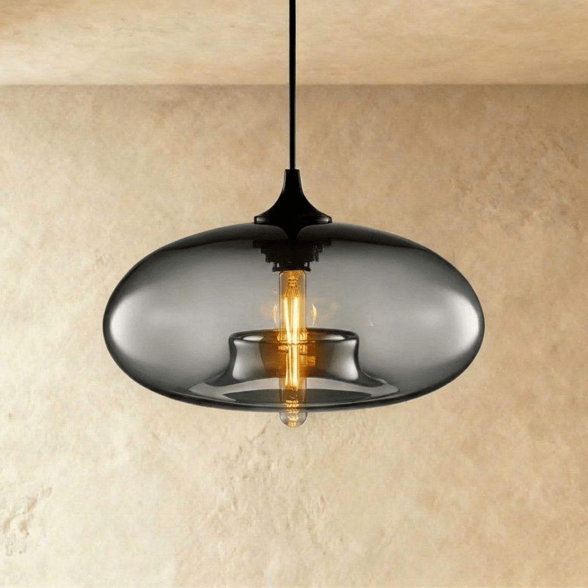 Clérachic pendant light with a smoked-grey oval glass shade lit by an amber tube bulb, black cord and cap above.