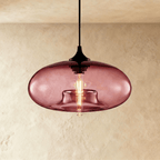 Clérachic pendant light with a dusky wine-red glass oval shade, black cord and cap, and a warm tube bulb glowing inside.