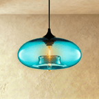 Clérachic pendant light with a bright aqua-blue glass oval shade, black cord and cap, and a warm tube bulb inside.
